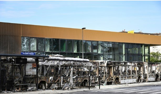 Macron returns to France as protesters destroy 12 buses